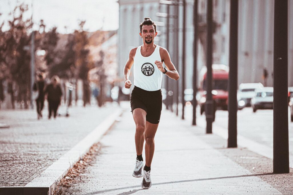 active young man running along asphalt sidewalk